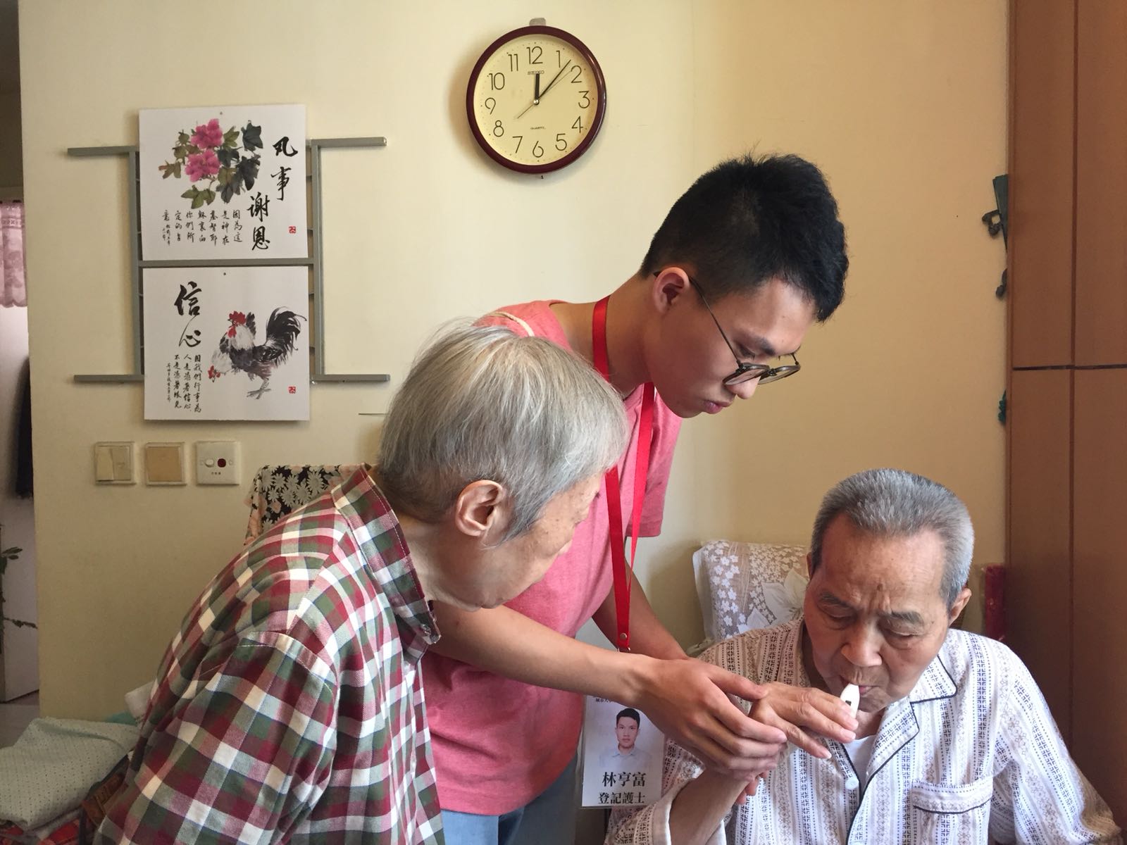 A nurse from the project team (middle) teaches an elderly and his caregiver how to administer medication during home visit.
